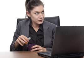 alcoholic business woman sneaking a drink at work sitting at her desk