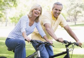 Middle age couple smiling and riding bikes